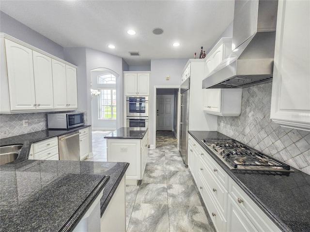 101 Covington Ln, Palm Coast, FL 32137 - kitchen with wall chimney range hood, appliances with stainless steel finishes, white cabinets, dark stone counters, and backsplash