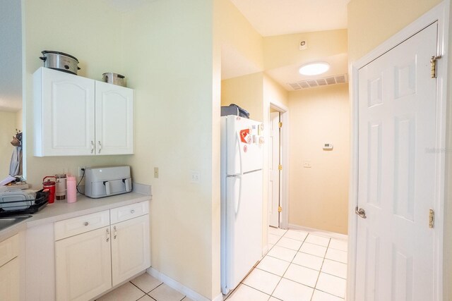 19 Rydell Ln, Palm Coast, FL 32164 - kitchen with freestanding refrigerator, white cabinetry, light tile patterned flooring, and light countertops