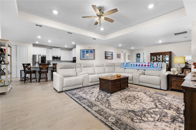 2137 Raglan Cir, Ormond Beach, FL 32174 - living room featuring ceiling fan, a tray ceiling, recessed lighting, and light wood-style flooring