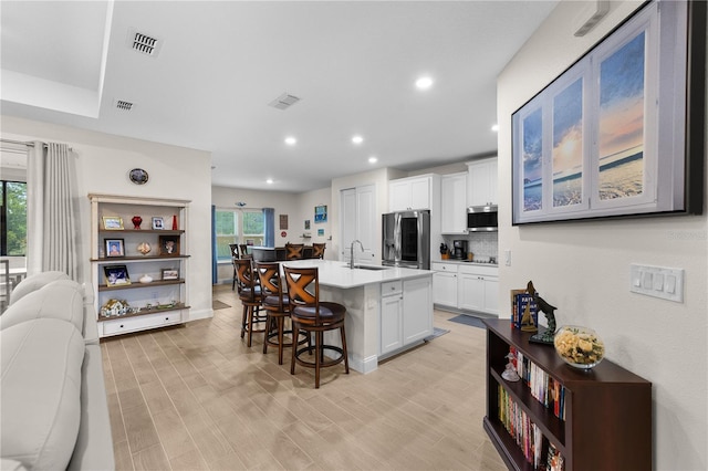 2137 Raglan Cir, Ormond Beach, FL 32174 - kitchen with stainless steel appliances, a kitchen bar, open floor plan, white cabinetry, and light countertops