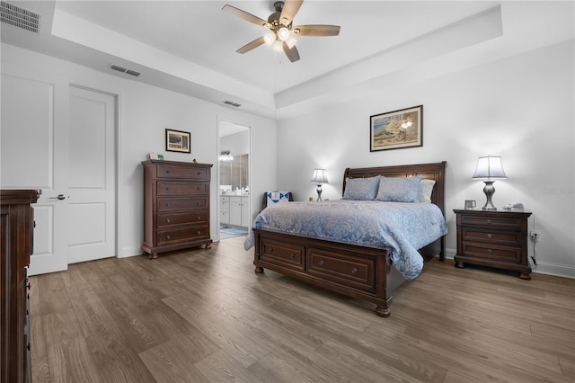 2137 Raglan Cir, Ormond Beach, FL 32174 - bedroom featuring a raised ceiling, wood finished floors, ensuite bath, and ceiling fan