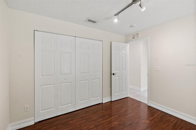 7 Zeolite Pl, Palm Coast, FL 32164 - unfurnished bedroom featuring dark wood-style flooring, a closet, a textured ceiling, and track lighting