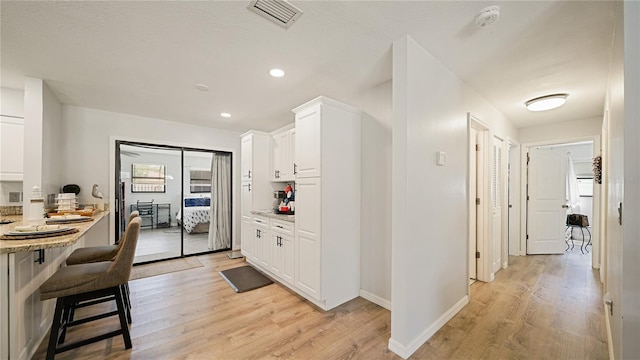 29 Firtree Ln, Palm Coast, FL 32137 - kitchen with light wood finished floors, white cabinetry, a kitchen breakfast bar, recessed lighting, and light stone counters