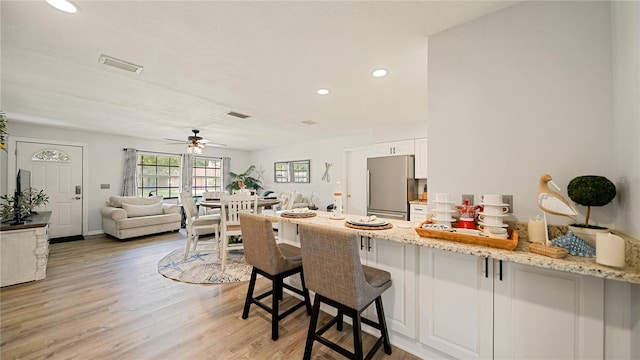 29 Firtree Ln, Palm Coast, FL 32137 - kitchen featuring freestanding refrigerator, a peninsula, a ceiling fan, a kitchen bar, and light wood-style flooring