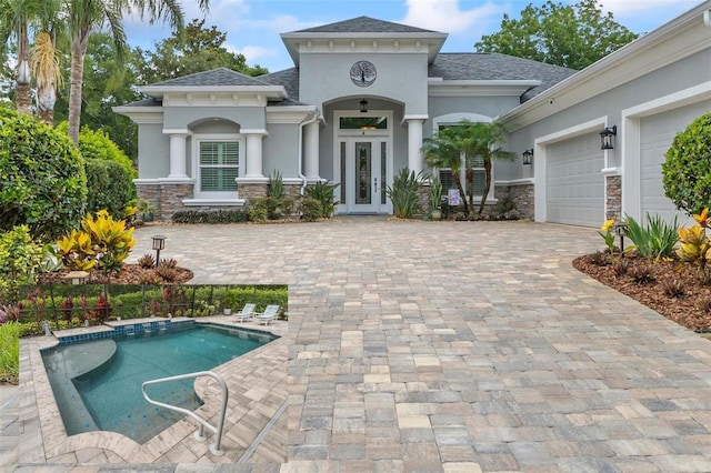 4 Midden Ln, Palm Coast, FL 32137 - view of front facade with stucco siding, french doors, an attached garage, decorative driveway, and roof with shingles