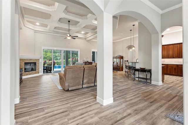 4 Midden Ln, Palm Coast, FL 32137 - living room featuring a ceiling fan, a stone fireplace, crown molding, a towering ceiling, and coffered ceiling