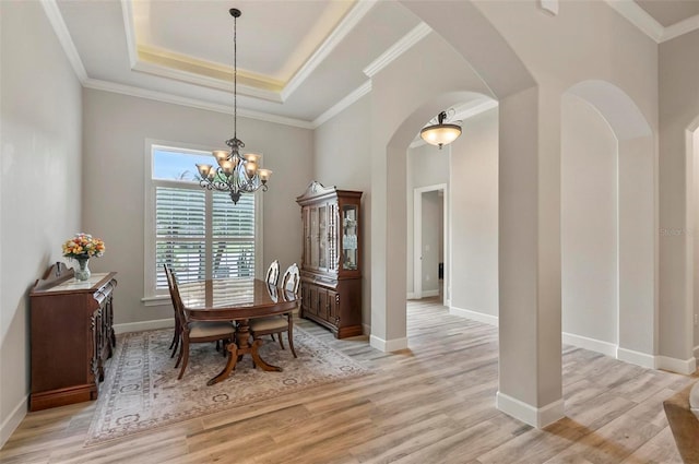 4 Midden Ln, Palm Coast, FL 32137 - dining area featuring a tray ceiling, arched walkways, a chandelier, light wood finished floors, and ornamental molding