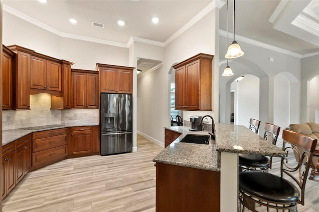 4 Midden Ln, Palm Coast, FL 32137 - kitchen with stainless steel fridge, a kitchen bar, arched walkways, a peninsula, and light stone countertops
