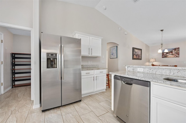 22 Post Tree Ln, Palm Coast, FL 32164 - kitchen with appliances with stainless steel finishes, lofted ceiling, white cabinetry, light stone counters, and arched walkways