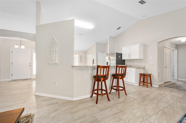 22 Post Tree Ln, Palm Coast, FL 32164 - kitchen featuring arched walkways, stainless steel fridge with ice dispenser, a kitchen breakfast bar, white cabinets, and high vaulted ceiling