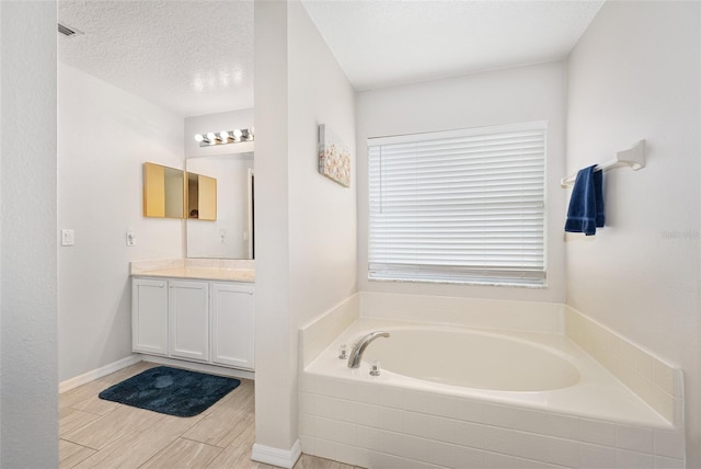 22 Post Tree Ln, Palm Coast, FL 32164 - bathroom with vanity, a garden tub, wood finished floors, and a textured ceiling