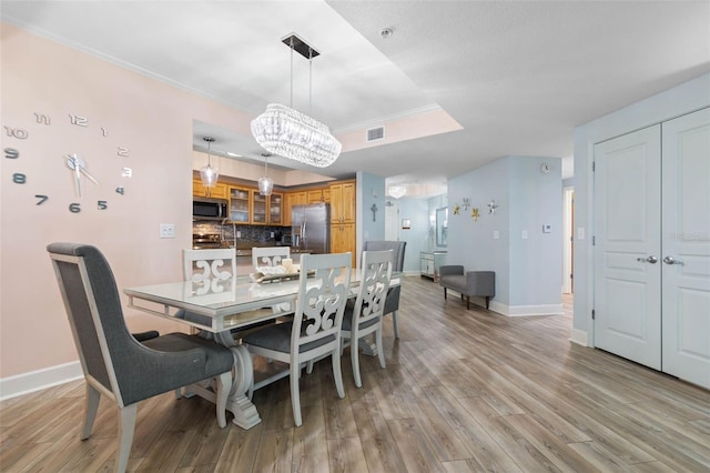 200 Ocean Crest Dr Unit 913, Palm Coast, FL 32137 - dining room with crown molding, light wood-style floors, a chandelier, and a tray ceiling