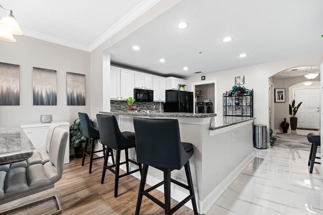 100 Bella Harbor Ct Unit 103, Palm Coast, FL 32137 - kitchen with black appliances, recessed lighting, arched walkways, ornamental molding, and backsplash