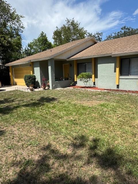1561 Copperfield Ave, Deltona, FL 32738 - view of front facade featuring a front yard, stucco siding, roof with shingles, and an attached garage