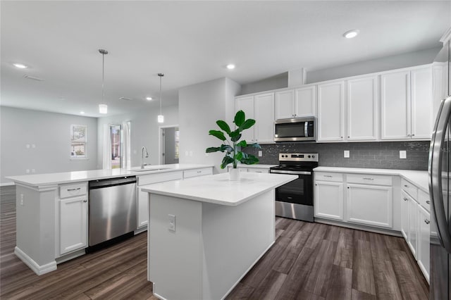 51 Oakleaf Way, Palm Coast, FL 32137 - kitchen featuring appliances with stainless steel finishes, a peninsula, dark wood-style floors, a center island, and light countertops