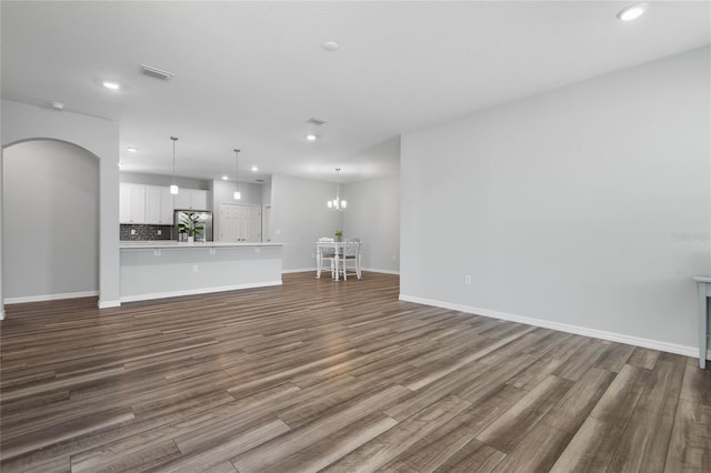51 Oakleaf Way, Palm Coast, FL 32137 - unfurnished living room with recessed lighting, dark wood finished floors, a chandelier, and arched walkways