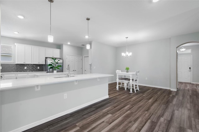 51 Oakleaf Way, Palm Coast, FL 32137 - kitchen with dark wood-type flooring, white cabinetry, light countertops, stainless steel fridge with ice dispenser, and arched walkways