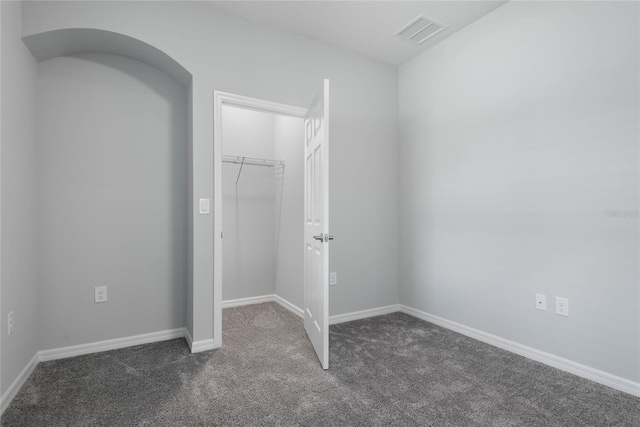 51 Oakleaf Way, Palm Coast, FL 32137 - unfurnished bedroom with dark carpet, a closet, and a walk in closet