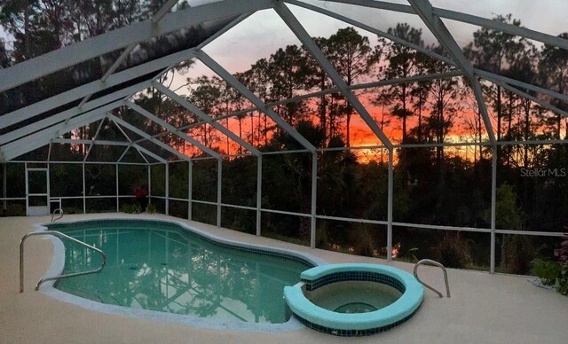 57 Prattwood Ln, Palm Coast, FL 32164 - pool at dusk with glass enclosure, a pool with connected hot tub, and a patio