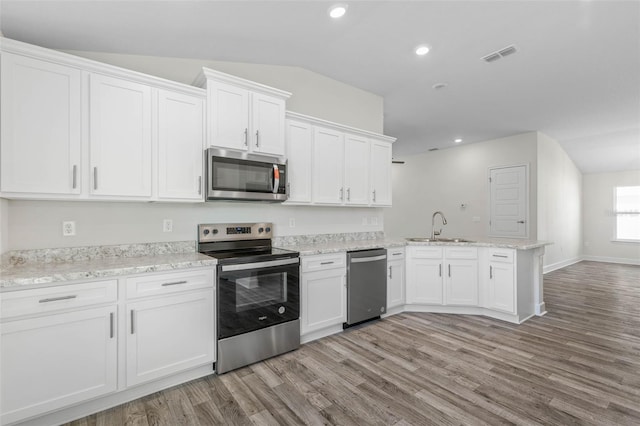 6 Bainbridge Ln, Palm Coast, FL 32137 - kitchen featuring stainless steel appliances, a peninsula, light wood-type flooring, white cabinetry, and vaulted ceiling