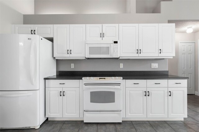 81 Brownstone Ln, Palm Coast, FL 32137 - kitchen with white appliances, dark countertops, and white cabinetry