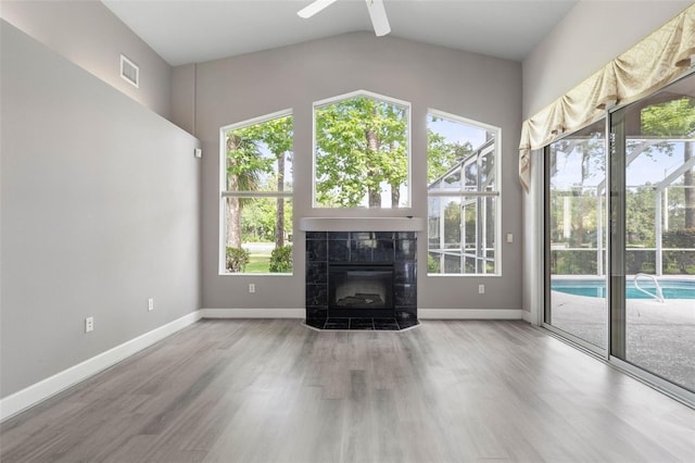 81 Brownstone Ln, Palm Coast, FL 32137 - unfurnished living room featuring wood finished floors, lofted ceiling, a tile fireplace, and ceiling fan