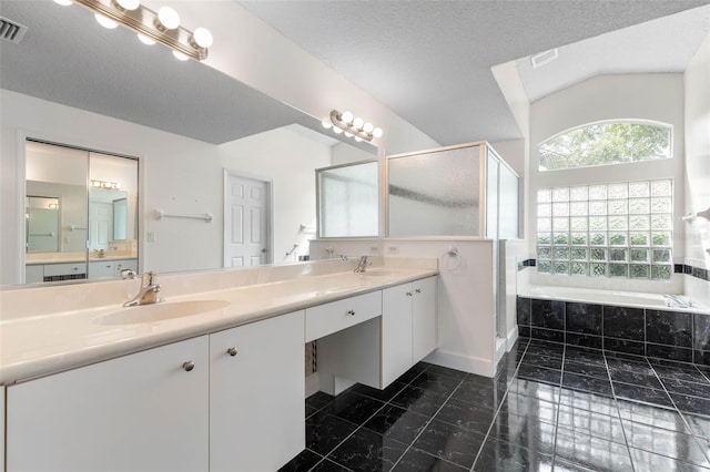81 Brownstone Ln, Palm Coast, FL 32137 - full bath with a garden tub, double vanity, a stall shower, vaulted ceiling, and a textured ceiling