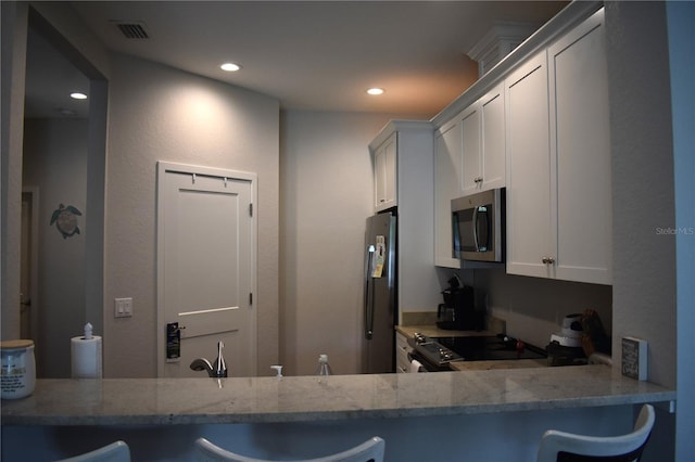 146 Via Madrid Dr, Ormond Beach, FL 32176 - kitchen featuring stainless steel microwave, electric range oven, freestanding refrigerator, recessed lighting, and light stone countertops