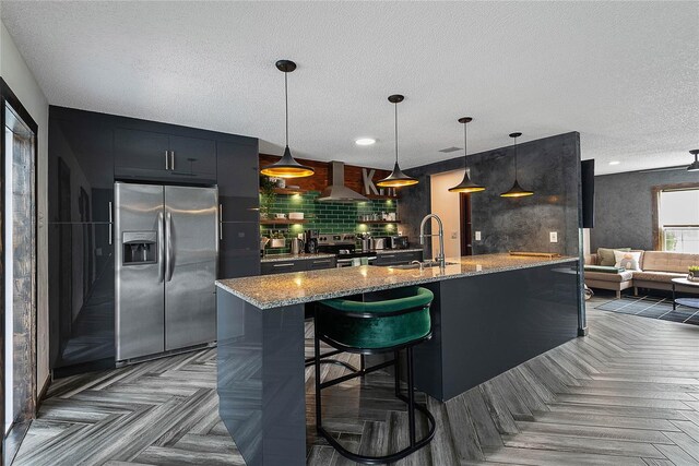 8 White Horse Ln, Palm Coast, FL 32164 - kitchen with stainless steel appliances, a textured ceiling, wall chimney range hood, decorative backsplash, and light stone countertops