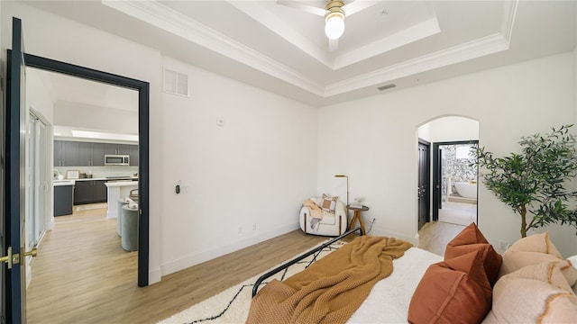 455 Riverfront Dr Unit A203, Palm Coast, FL 32137 - bedroom featuring arched walkways, light wood-style flooring, a raised ceiling, crown molding, and connected bathroom