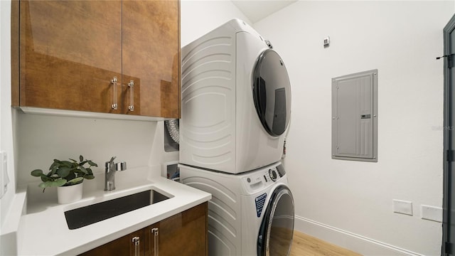 455 Riverfront Dr Unit A203, Palm Coast, FL 32137 - laundry room featuring stacked washer and clothes dryer, electric panel, cabinet space, and light wood-type flooring