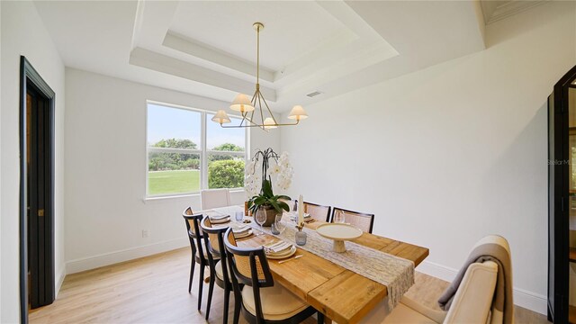455 Riverfront Dr Unit A204, Palm Coast, FL 32137 - dining area featuring a chandelier, light wood-style flooring, and a tray ceiling