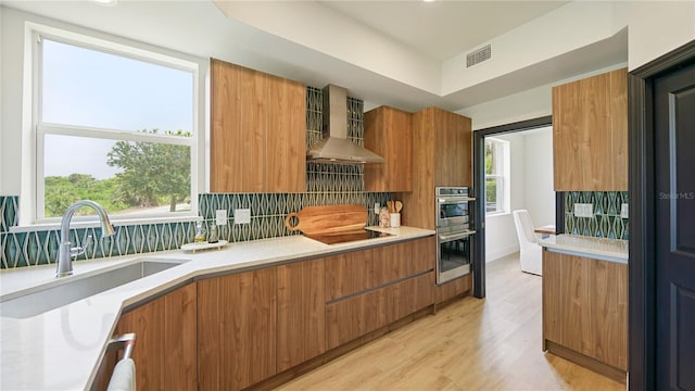 455 Riverfront Dr Unit A204, Palm Coast, FL 32137 - kitchen with stainless steel double oven, modern cabinets, brown cabinets, wall chimney exhaust hood, and black electric stovetop