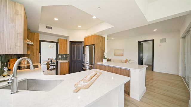 455 Riverfront Dr Unit A204, Palm Coast, FL 32137 - kitchen with high quality fridge, a peninsula, brown cabinets, modern cabinets, and light wood-style floors