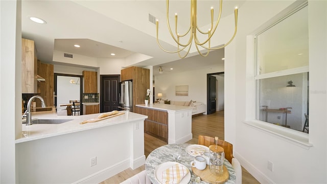 455 Riverfront Dr Unit A204, Palm Coast, FL 32137 - kitchen featuring a peninsula, high end fridge, modern cabinets, brown cabinets, and light wood finished floors