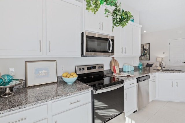 88 Rae Dr, Palm Coast, FL 32164 - kitchen featuring appliances with stainless steel finishes, light stone counters, white cabinets, and light tile patterned floors