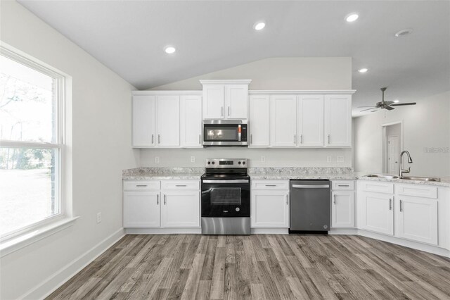 12 Wainshire Pl, Palm Coast, FL 32164 - kitchen with stainless steel appliances, lofted ceiling, white cabinetry, light wood finished floors, and light stone countertops