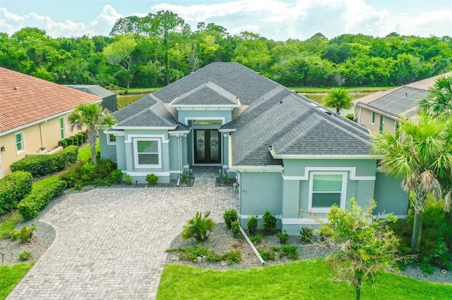 67 N Lakewalk Dr, Palm Coast, FL 32137 - view of front of home featuring stucco siding, a shingled roof, french doors, and driveway