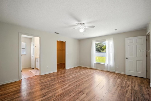 37 Lindsay Dr, Palm Coast, FL 32137 - unfurnished bedroom featuring wood finished floors, a spacious closet, a textured ceiling, ceiling fan, and a closet