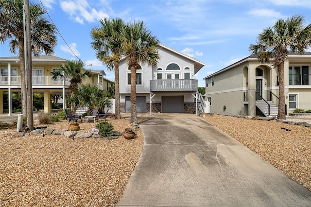 1115 N Central Ave, Flagler Beach, FL 32136 - view of front facade with stucco siding, driveway, a balcony, a garage, and stone siding