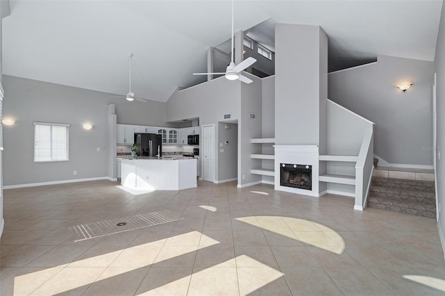 1115 N Central Ave, Flagler Beach, FL 32136 - unfurnished living room featuring ceiling fan, light tile patterned floors, high vaulted ceiling, built in shelves, and a glass covered fireplace