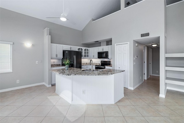 1115 N Central Ave, Flagler Beach, FL 32136 - kitchen featuring black appliances, light tile patterned floors, light stone countertops, glass insert cabinets, and high vaulted ceiling