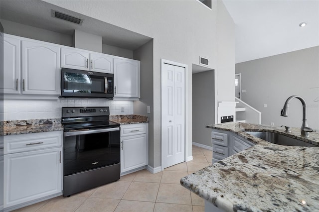 1115 N Central Ave, Flagler Beach, FL 32136 - kitchen with black appliances, stone countertops, light tile patterned floors, and a high ceiling