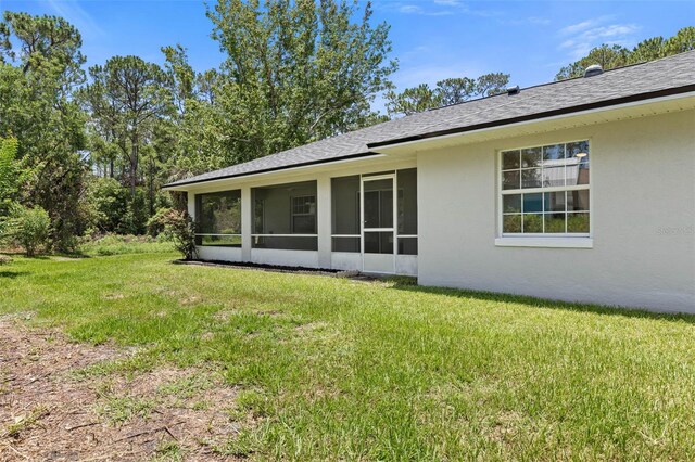 23 Pennfield Ln, Palm Coast, FL 32164 - back of house with a sunroom, a lawn, stucco siding, and roof with shingles