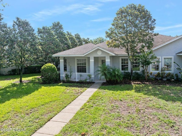 3132 Connemara Dr, Ormond Beach, FL 32174 - view of front of property with covered porch, a front lawn, stucco siding, and roof with shingles