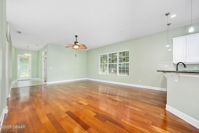 3132 Connemara Dr, Ormond Beach, FL 32174 - unfurnished living room with a chandelier, wood finished floors, and a ceiling fan