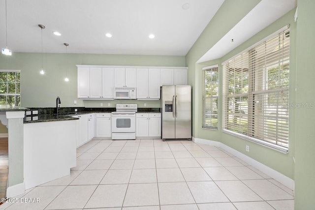 3132 Connemara Dr, Ormond Beach, FL 32174 - kitchen featuring white appliances, a peninsula, dark countertops, hanging light fixtures, and white cabinetry