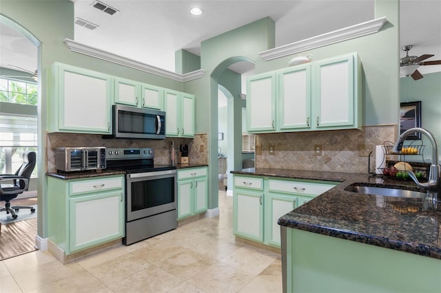 5 Senora Ct, Palm Coast, FL 32164 - kitchen featuring appliances with stainless steel finishes, ceiling fan, dark stone countertops, arched walkways, and decorative backsplash