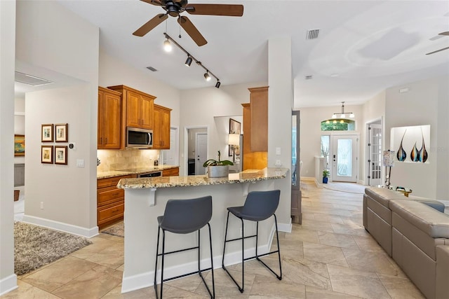 1254 Royal Pointe Ln, Ormond Beach, FL 32174 - kitchen featuring appliances with stainless steel finishes, a ceiling fan, brown cabinets, and open floor plan