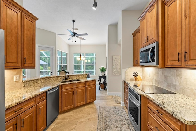 1254 Royal Pointe Ln, Ormond Beach, FL 32174 - kitchen featuring stainless steel appliances, brown cabinets, a ceiling fan, and a peninsula